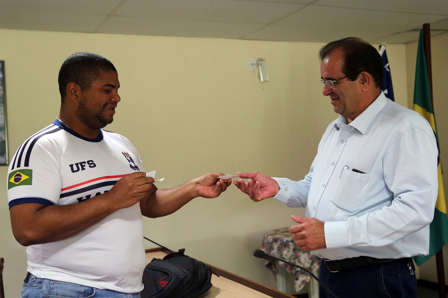 Atleta de handebol Breno Rafael entrega ao reitor Angelo Antoniolli um adesivo como forma de demonstrar a união que o esporte deve trazer aos atletas universitários. (fotos: Schirlene Reis/Ascom/UFS)